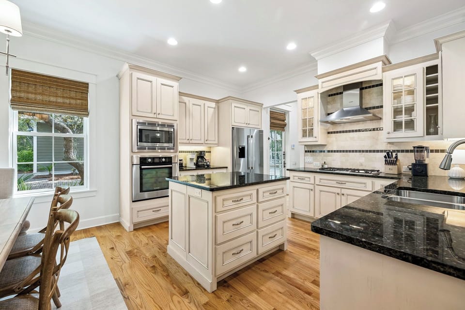 Step into your dream chef's kitchen with elegant white cabinetry, gleaming granite countertops, and premium stainless steel appliances. The spacious island provides perfect prep space while warm wood floors complete this inviting culinary haven.