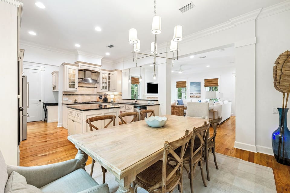 Gather around the warm, weathered wood dining table where your group can share laughter and meals together, flowing seamlessly into the bright, fully-equipped kitchen—your home base for coastal living.