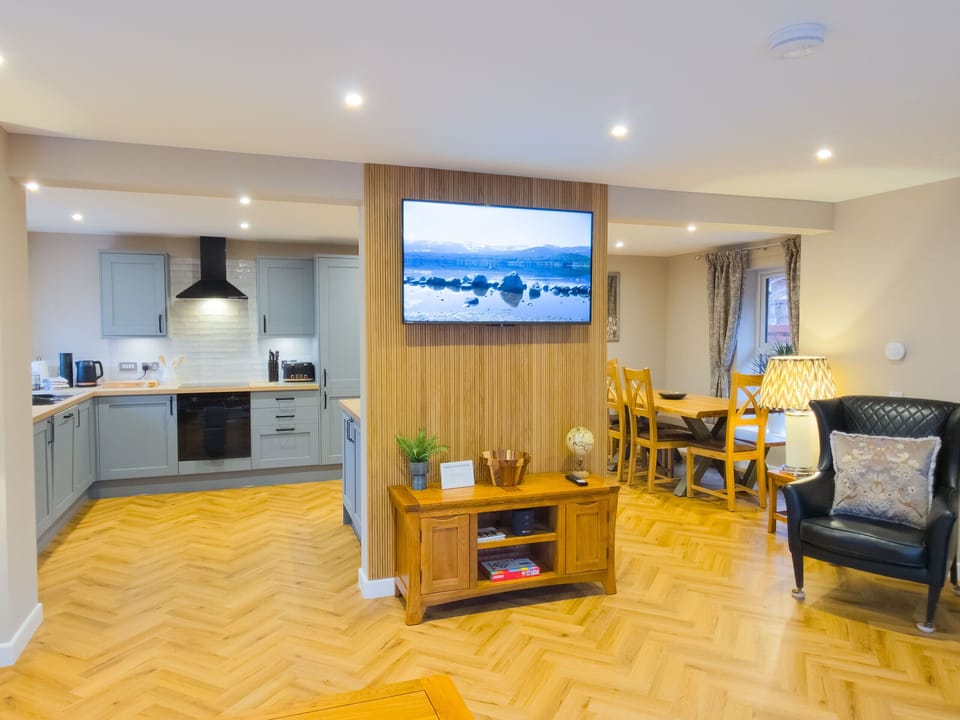 The open-plan kitchen and dining area at Kestrel Lodge offers a wonderful space for family meals. The fully fitted kitchen with grey shaker units and integrated appliances sits alongside the dining area with its solid wood table and chairs, all set on beautiful herringbone parquet flooring. Perfect for gathering the family together to plan the next day's adventures in the Scottish Highlands.