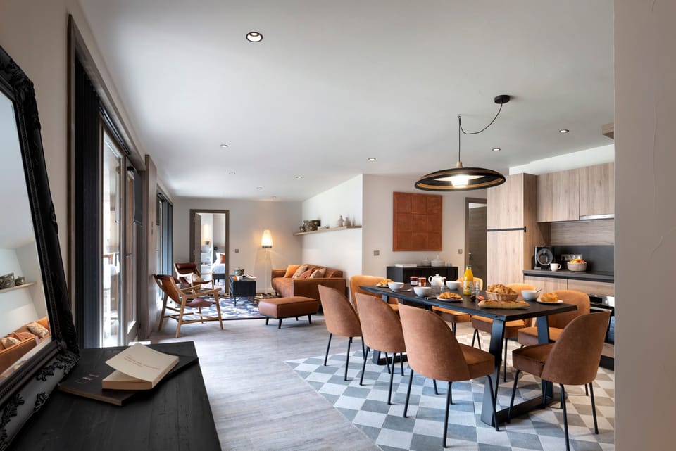 Long black dining table seats the whole group of eight — large windows bring in the alpine light