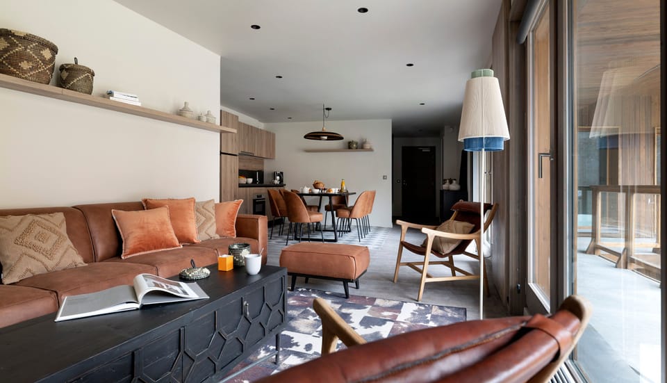 Brown leather sectional sofa, black coffee table, and layered cushions in the main living area