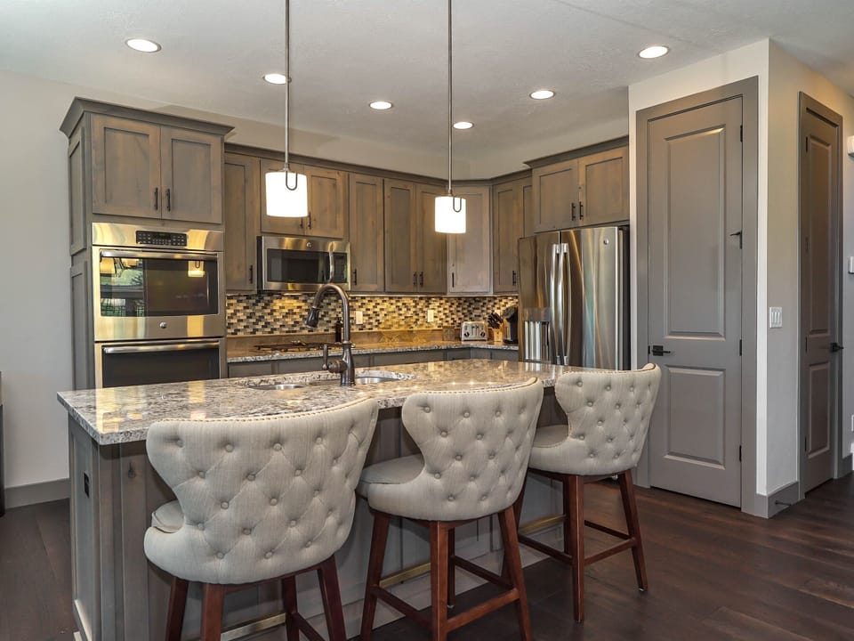 Modern kitchen with granite countertops and stylish bar seating for 3.