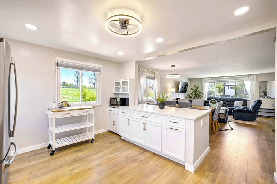 Kitchen, dining, and living areas connect seamlessly across the main level. White cabinetry, a central island, and a high chair at the counter make this a practical and welcoming hub for families and groups alike.