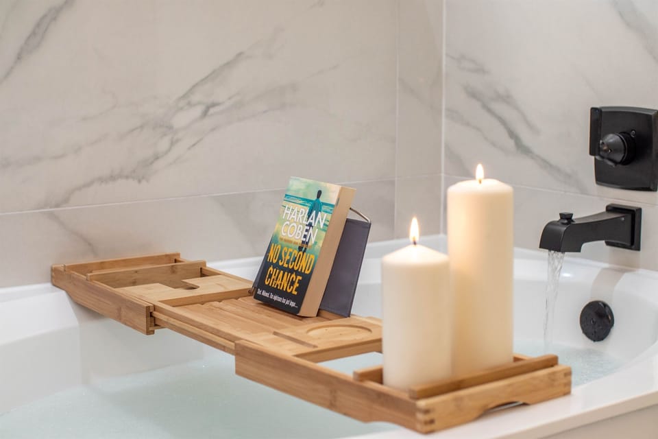 A relaxing soaking tub setup with a bath tray, candles, and a good book—perfect for unwinding and enjoying a peaceful spa-like moment.