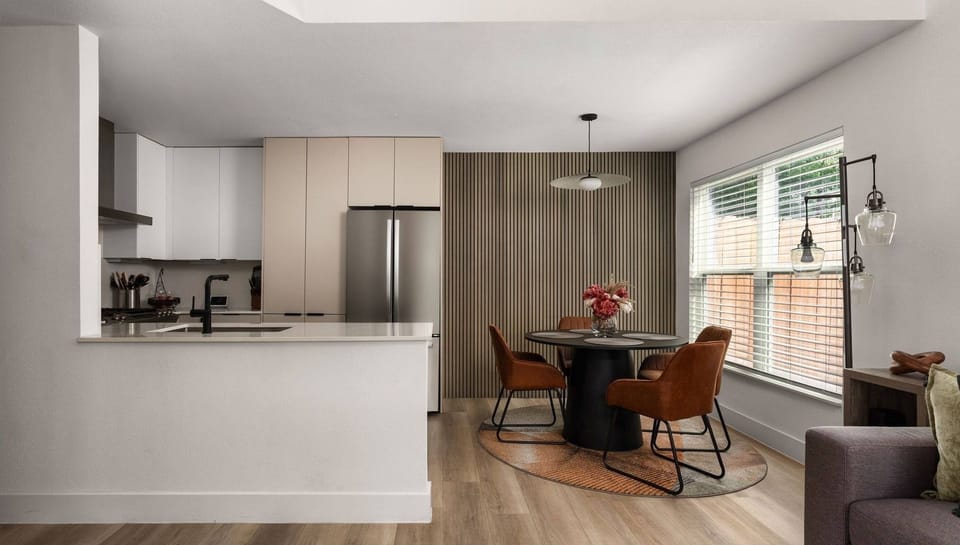 Sun-filled dining nook seamlessly connected to the kitchen — a bright and functional space for everyday meals with warm wood floors, a statement pendant light, and an open layout that makes hosting feel effortless.