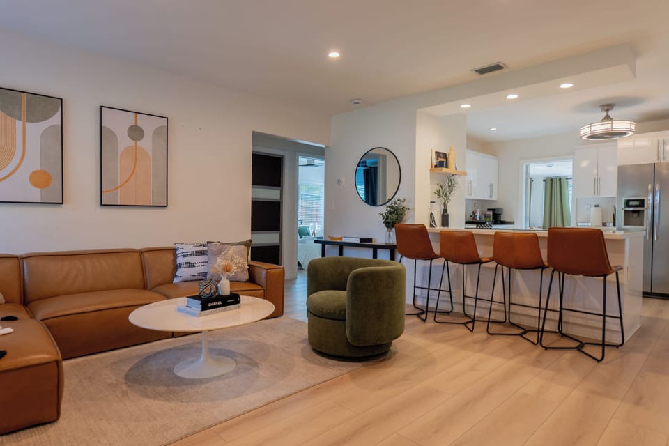 Open living area with sectional sofa, swivel chair, and kitchen bar seating
