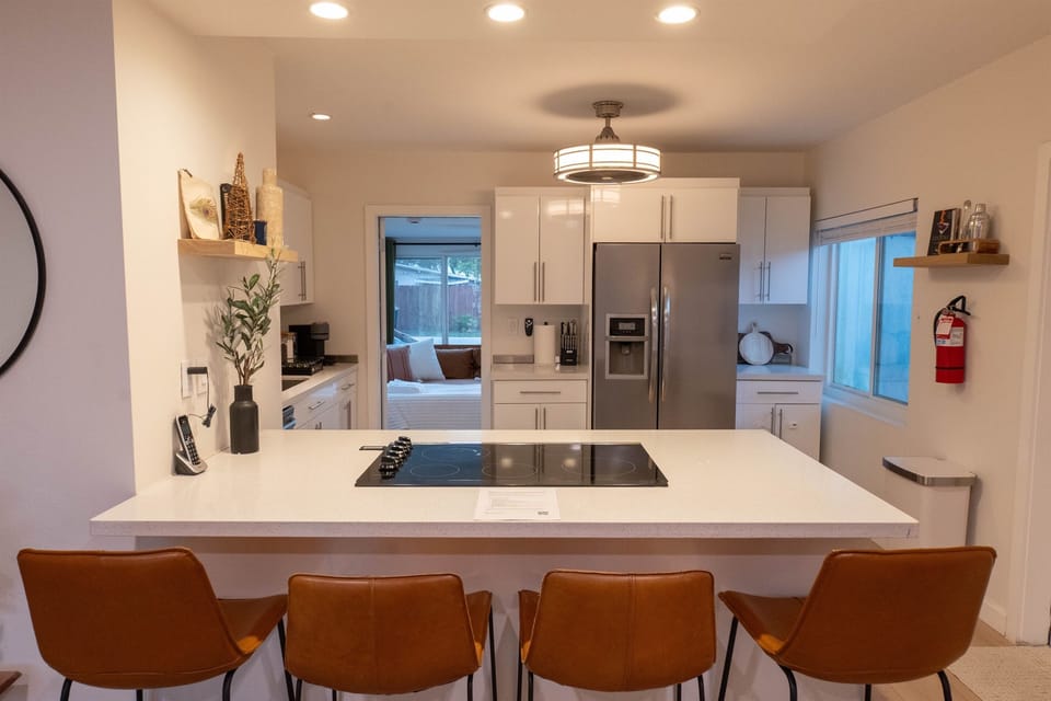 Kitchen with bar seating, large island cooktop, and stainless appliances.