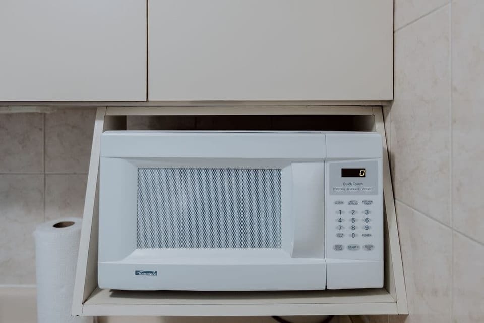 White microwave in Isla Verde kitchenette, perfect for quick snacks and reheating leftovers after a beach day.