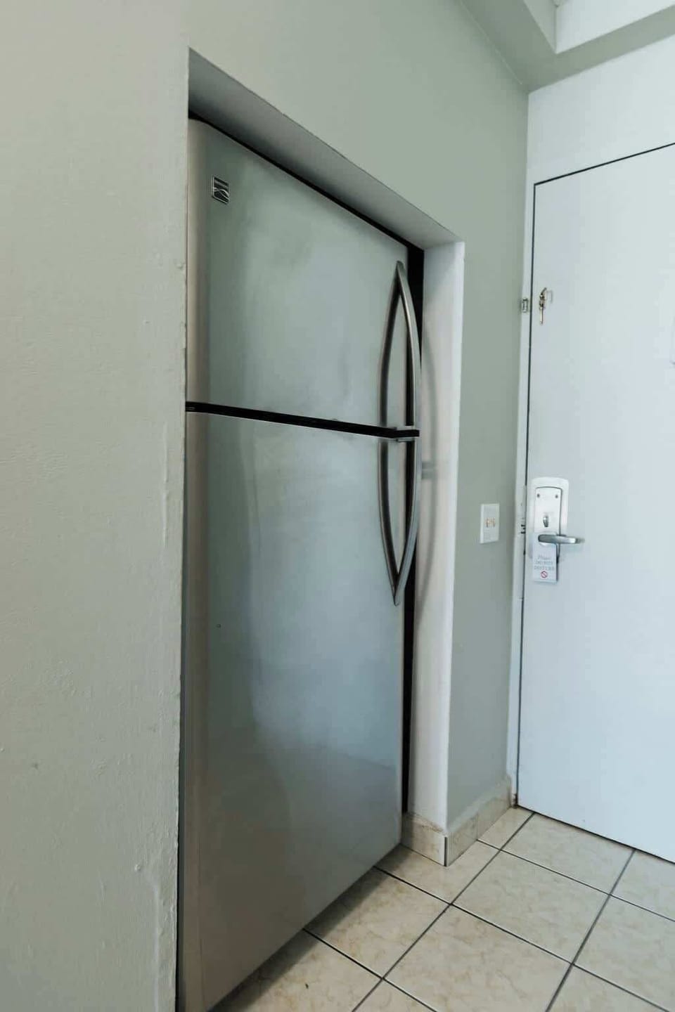 Full‑size stainless‑steel refrigerator by the entryway offers plenty of space for groceries, drinks, and leftovers during your stay.