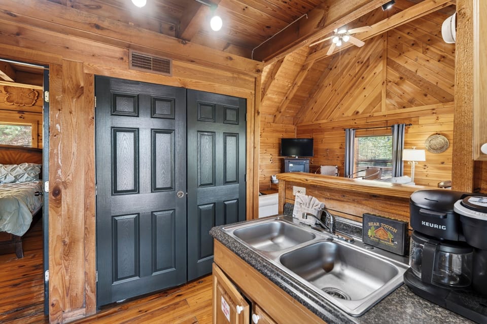 Rustic cabin kitchen with warm wood tones, simple comforts, and a cozy, lived‑in mountain charm. (Elianah's Cabin)