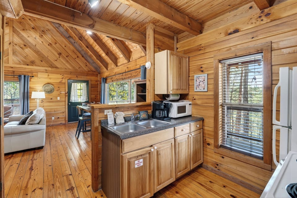 Rustic cabin kitchen with warm wood tones, simple comforts, and a cozy, lived‑in mountain charm. (Elianah's Cabin)