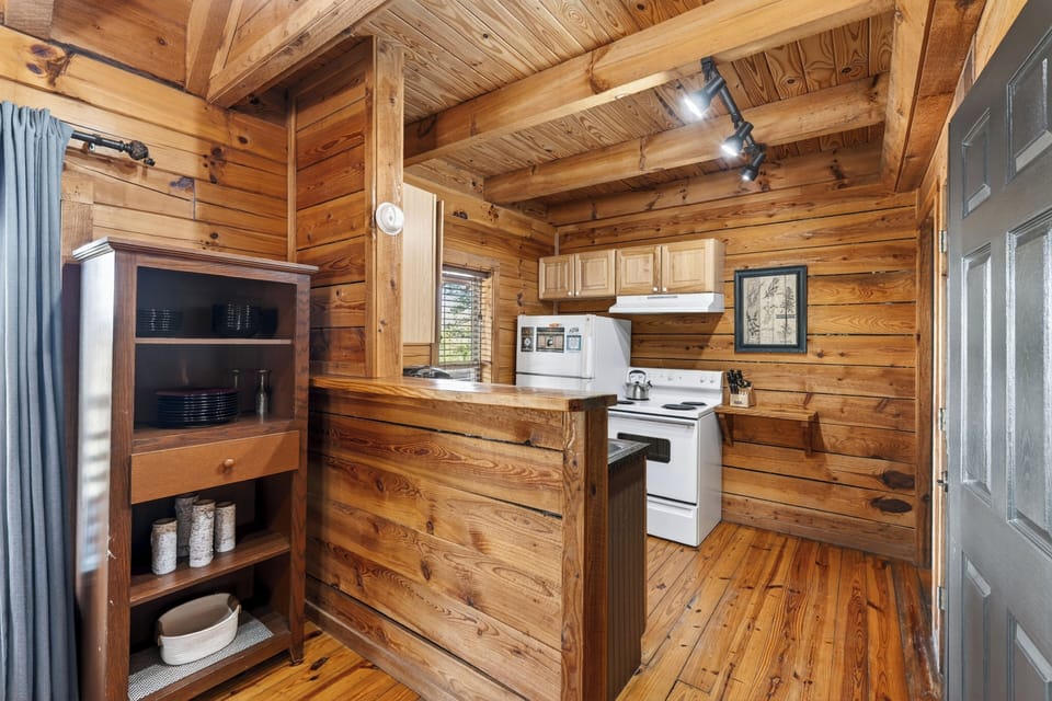 Rustic cabin kitchen with warm wood tones, simple comforts, and a cozy, lived‑in mountain charm. (Elianah's Cabin)