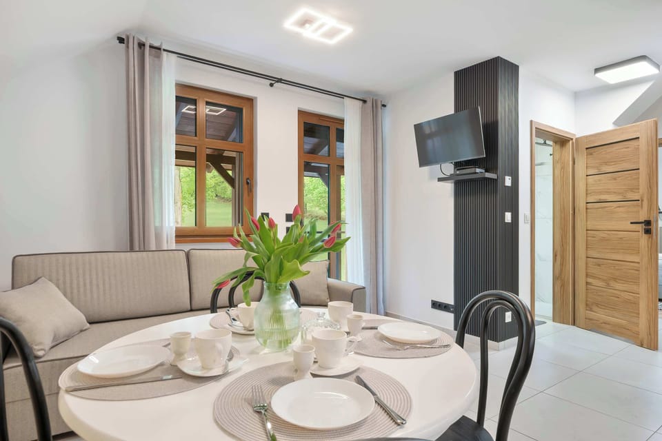 A dining corner with elegant table settings placed beside large balcony doors.