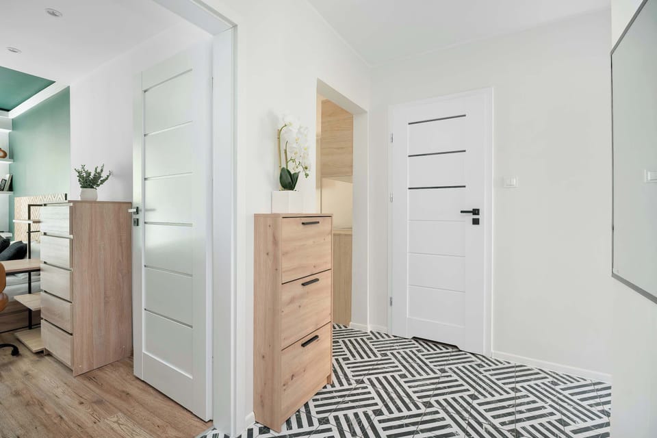 Bright hallway with geometric floor tiles leads towards different rooms, reflecting a clean and modern aesthetic.