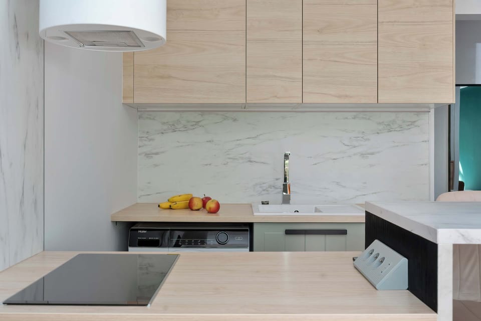 A close-up of the kitchenette workspace shows a light wood countertop, an integrated stove, and modern cabinetry.