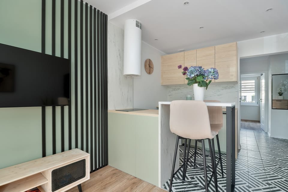 Slats on the wall create a stylish divider between the kitchen zone and the living area near the television.