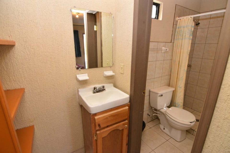 Open interior combining living, sleeping, and kitchenette spaces in this ground-floor studio — includes A/C, full bathroom, and secure gated parking