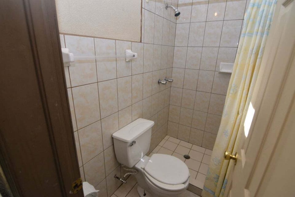 Full bathroom features a walk‑in shower, modern vanity, and toilet — part of this ground‑floor downtown studio rental with A/C, kitchenette, and secure gated parking .