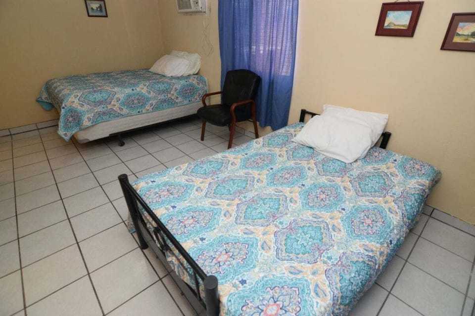 Features a queen bed and 2 twin beds — comfortable for up to 4 guests. Includes A/C, private kitchen, and secure gated parking.