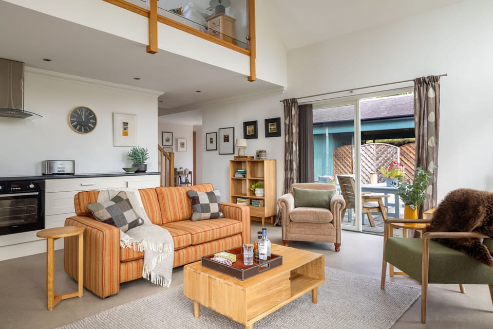 The light-filled open-plan living space with comfortable seating, natural textures, and French doors leading to the terrace