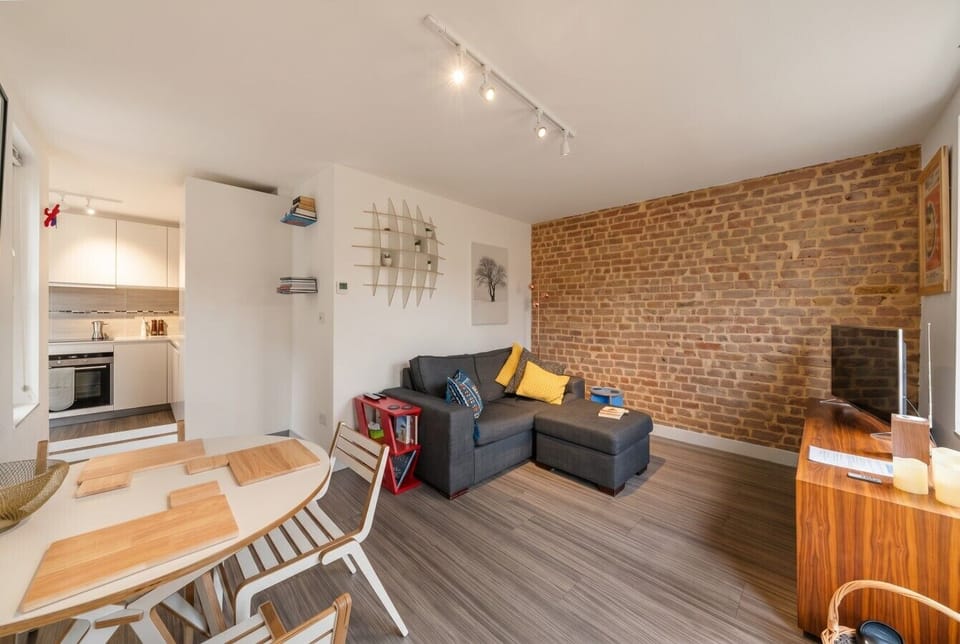 Open plan lounge and dining area anchored by a stunning original exposed brick wall.