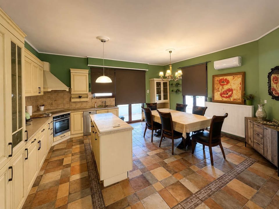 Spacious country-style kitchen with dining area and warm green accents