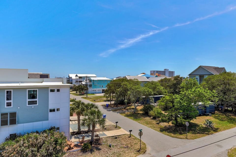 A coastal neighborhood setting with lush greenery, nearby beach access, and a variety of residential buildings, offering a relaxed seaside community atmosphere.