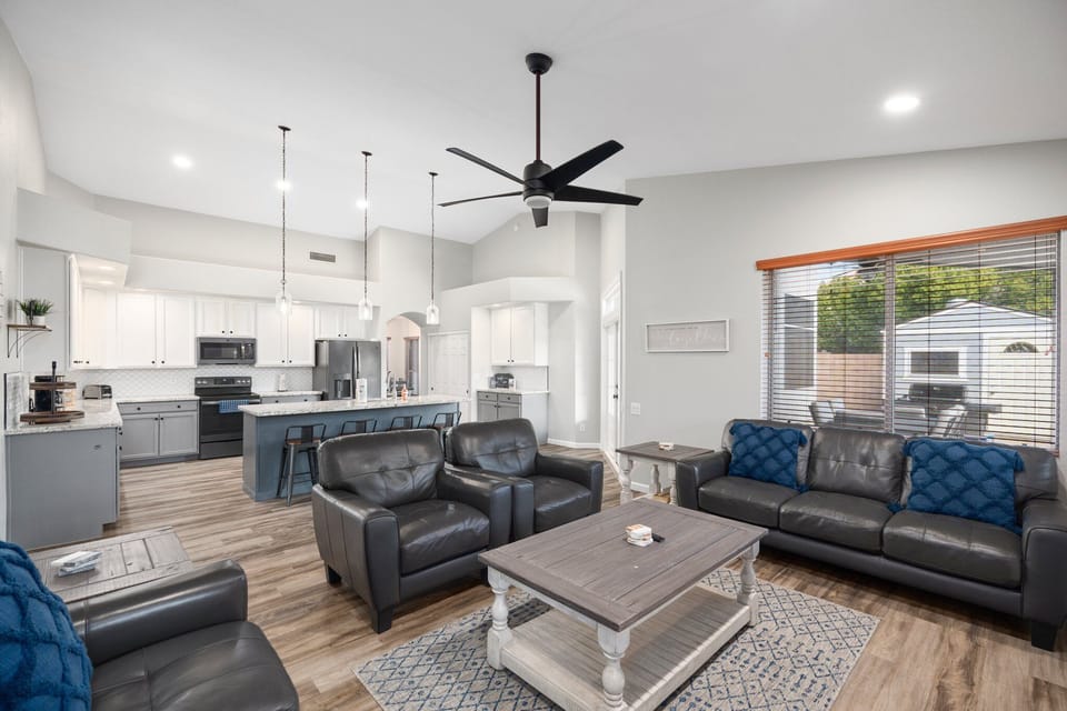 The bright, open-concept living space features vaulted ceilings, cozy leather seating, and a fully equipped kitchen—perfect for gathering with family after a day of adventure.