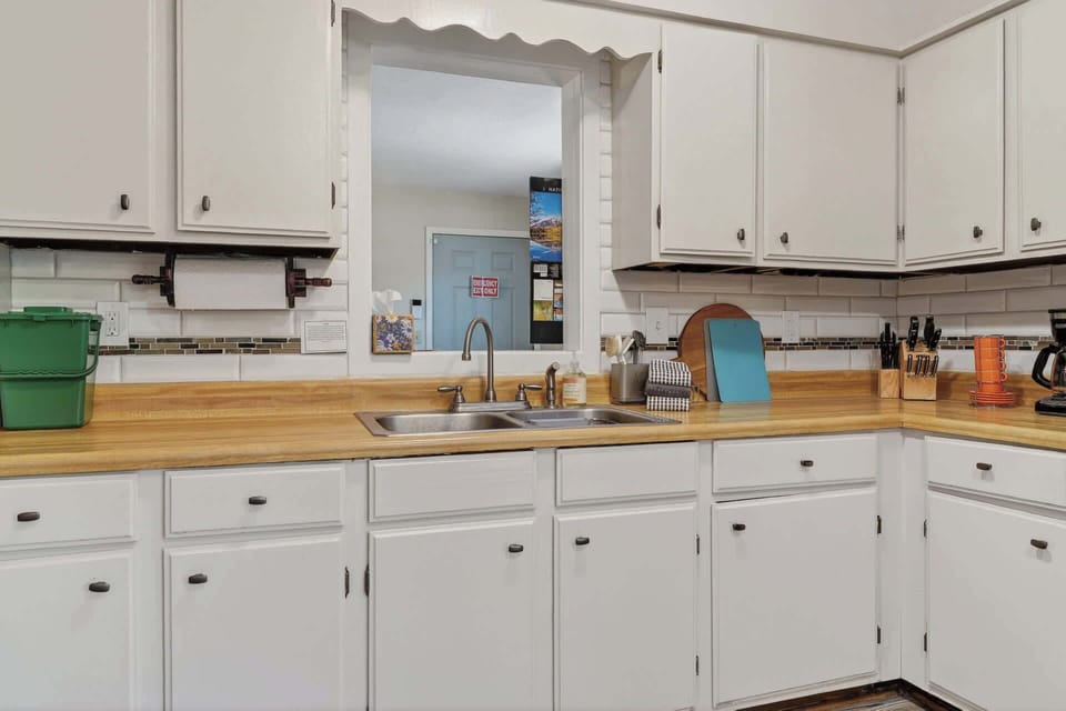 Cook your favorite meals in this well-equipped kitchen featuring warm butcher-block counters, classic white cabinetry, and all the essentials for your stay.
