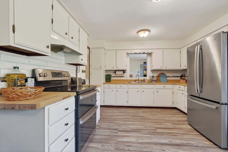 This spacious kitchen invites you to cook and gather with butcher block counters, stainless appliances, and warm wood floors throughout.
