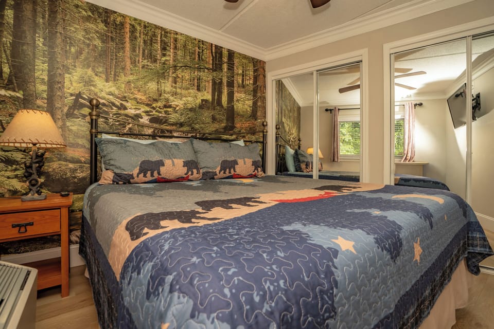 Cozy woodland retreat where nature meets comfort. A forest mural and plush bear-motif bedding create a serene sanctuary, while warm wood accents and soft lighting offer the perfect respite after mountain adventures.