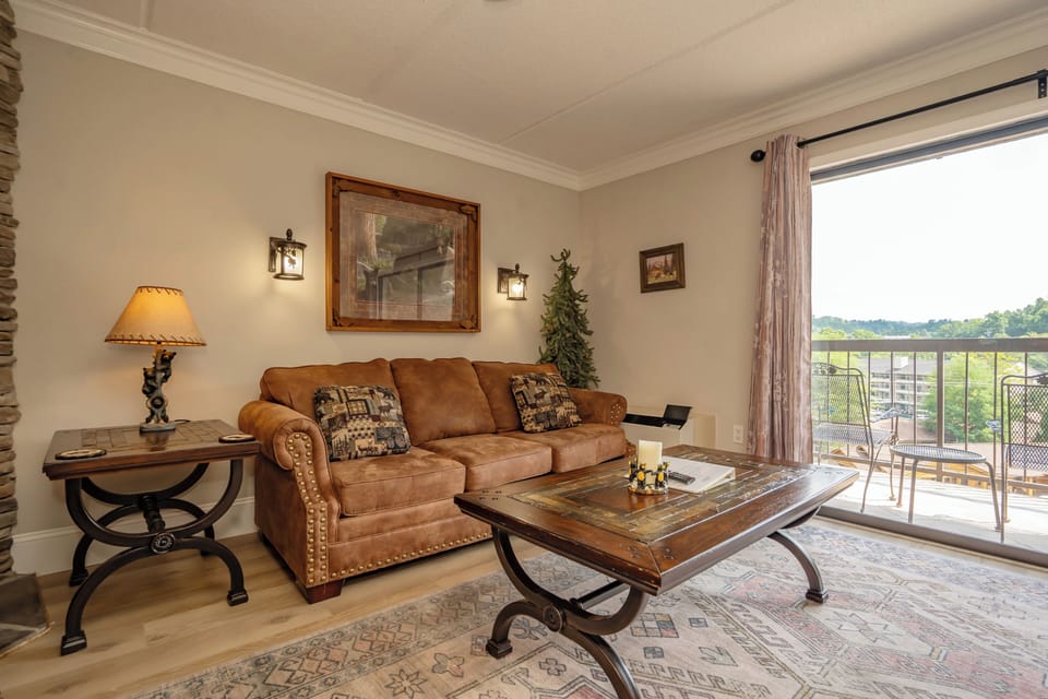 Sink into the plush sofa and unwind in your cozy living space, where rustic charm meets comfort and sweeping views of green fields stretch beyond your private balcony.