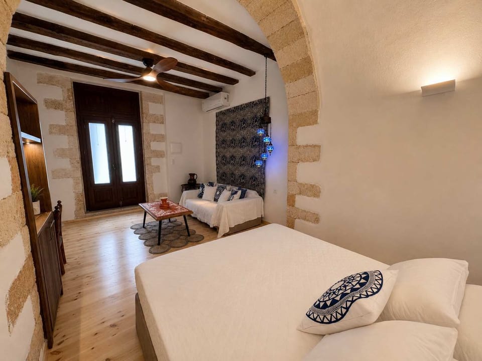 Bright bedroom with a comfortable bed, exposed wooden beams, and wooden furnishings, creating a warm and authentic atmosphere.