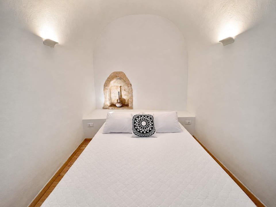 Bright bedroom with a comfortable bed, exposed wooden beams, and wooden furnishings, creating a warm and authentic atmosphere.