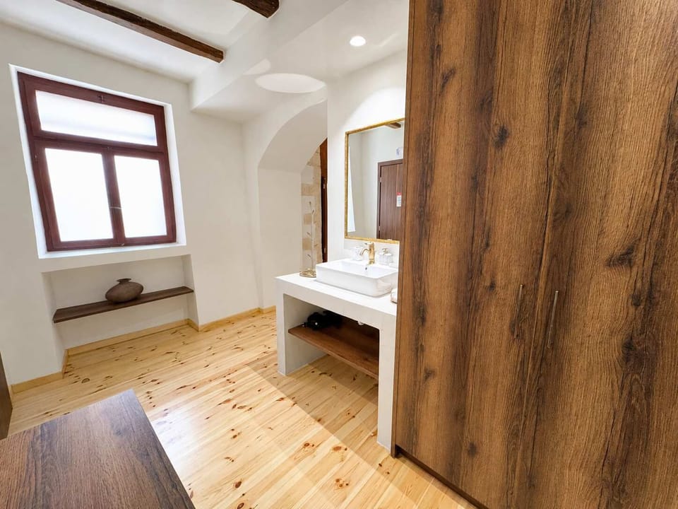 Bright bedroom with a comfortable bed, exposed wooden beams, and wooden furnishings, creating a warm and authentic atmosphere.