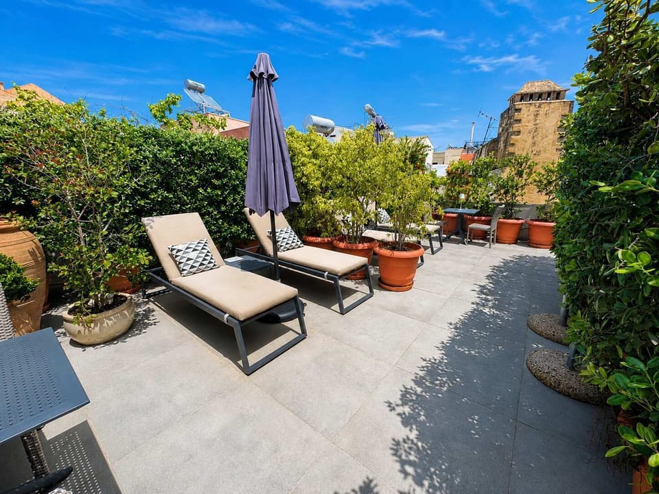 Relaxing area with sun loungers and umbrella on the shared rooftop terrace, ideal for enjoying the Mediterranean weather