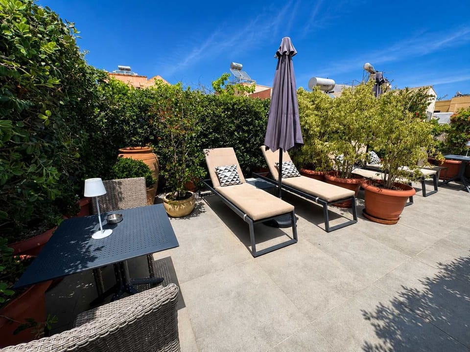Relaxing area with sun loungers and umbrella on the shared rooftop terrace, ideal for enjoying the Mediterranean weather