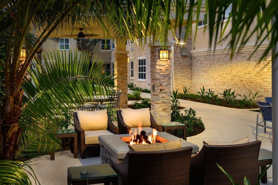 The cozy outdoor fire pit area, surrounded by lush greenery, provides a warm and intimate spot for evening gatherings.