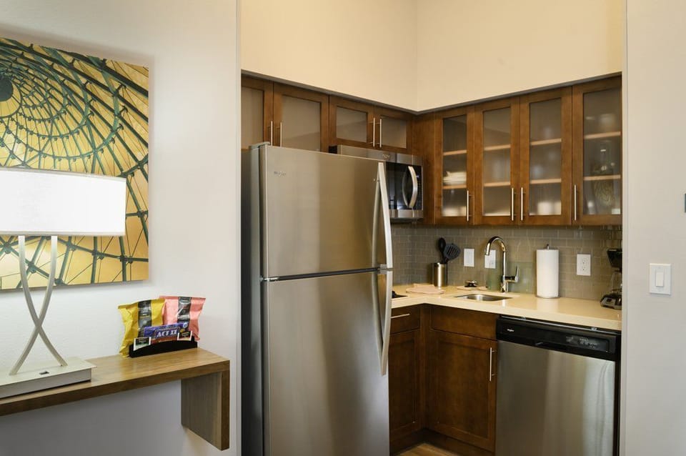 The kitchen features stainless steel appliances, including a refrigerator and dishwasher, paired with sleek wooden cabinetry.