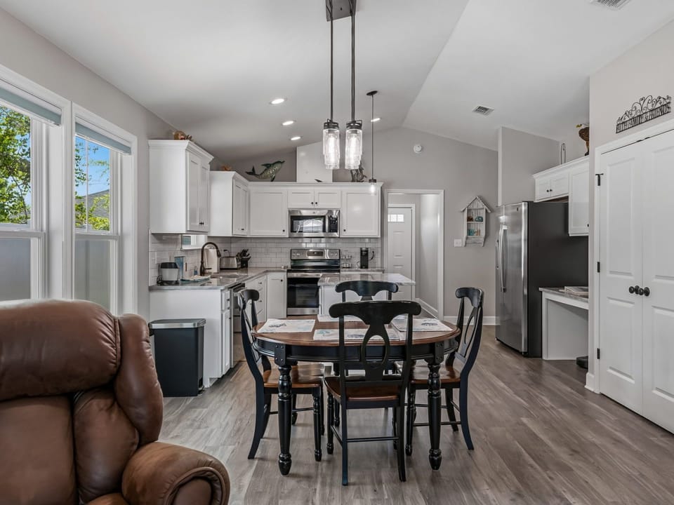 Open-plan kitchen and dining area with black countertops, white cabinetry, and a large central island
