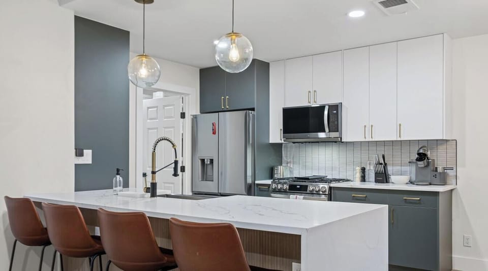 The waterfall quartz island seats four at the bar and doubles as the heart of the kitchen`s prep space.