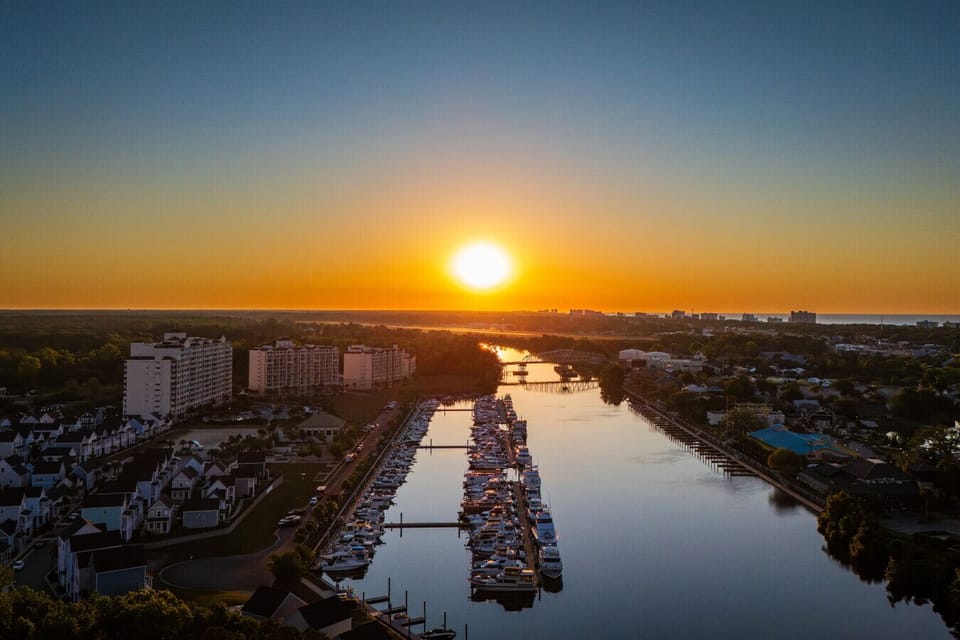 Sunrise over Barefoot Marina, with the Intracoastal Waterway stretching toward the Atlantic horizon and the full marina reflected in the still water below.