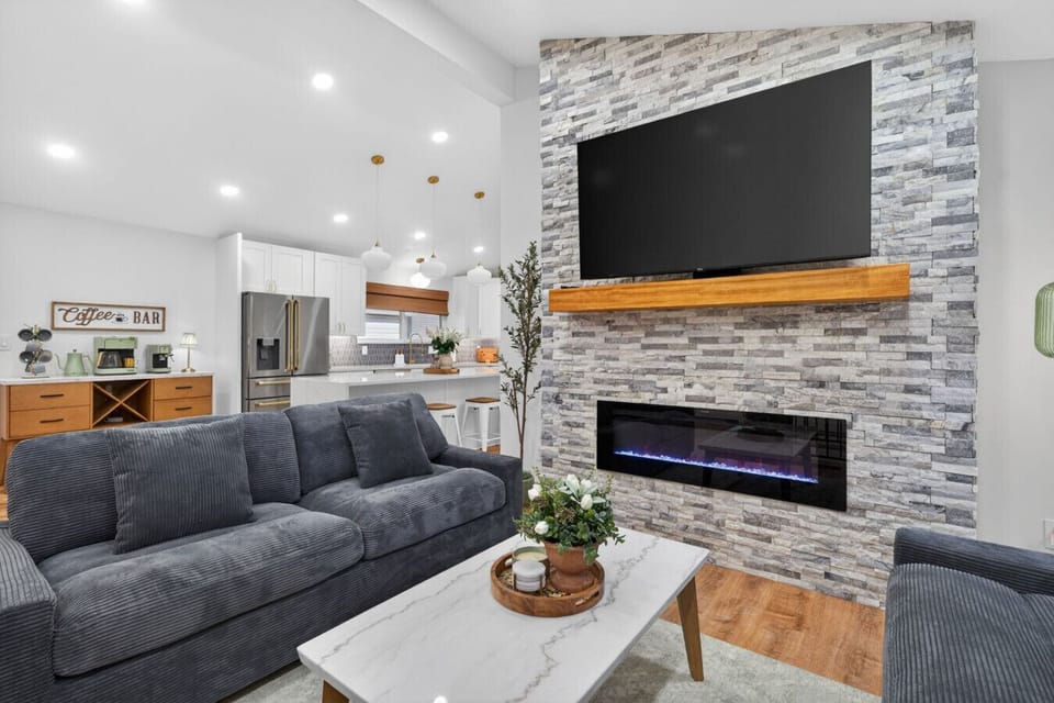 Open-concept living and kitchen designed for effortless entertaining! Plush sleeper sofas, a stunning stacked stone fireplace with mounted TV, and seamless flow into the chef`s kitchen and coffee bar. Vaulted ceilings make hosting a true delight