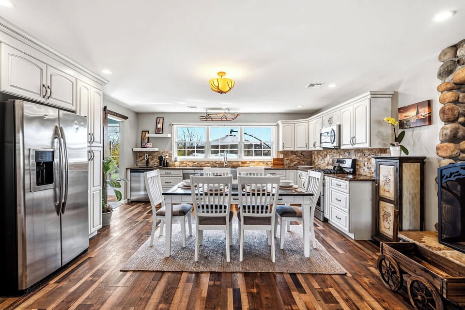 Kitchen with white cabinets, stone backsplash, and stainless appliances