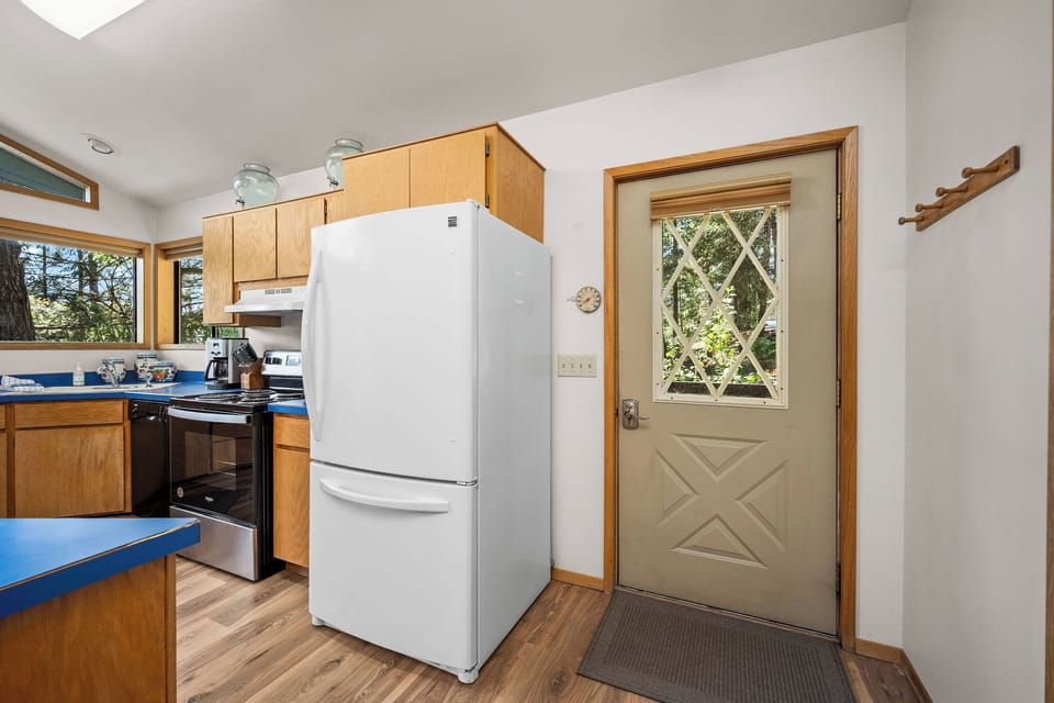 This bright kitchen offers everything you need to prepare meals in comfort, with a welcoming view of lush greenery through the charming diamond-pane door.