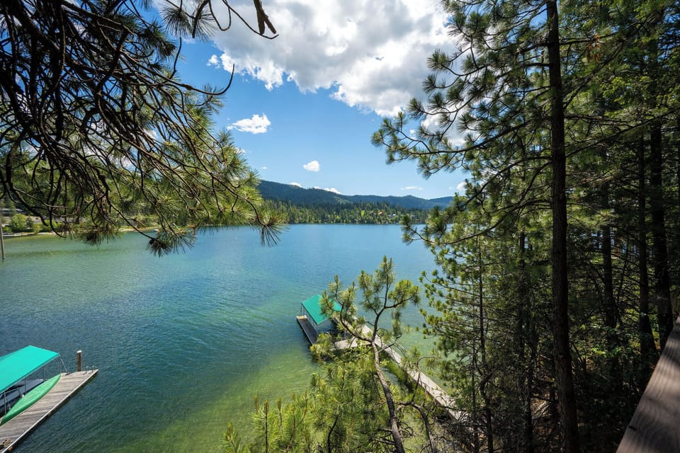 Private lakefront property featuring a serene natural setting with pine-framed vistas, mountain backdrop, and exclusive dock access on tranquil turquoise waters.