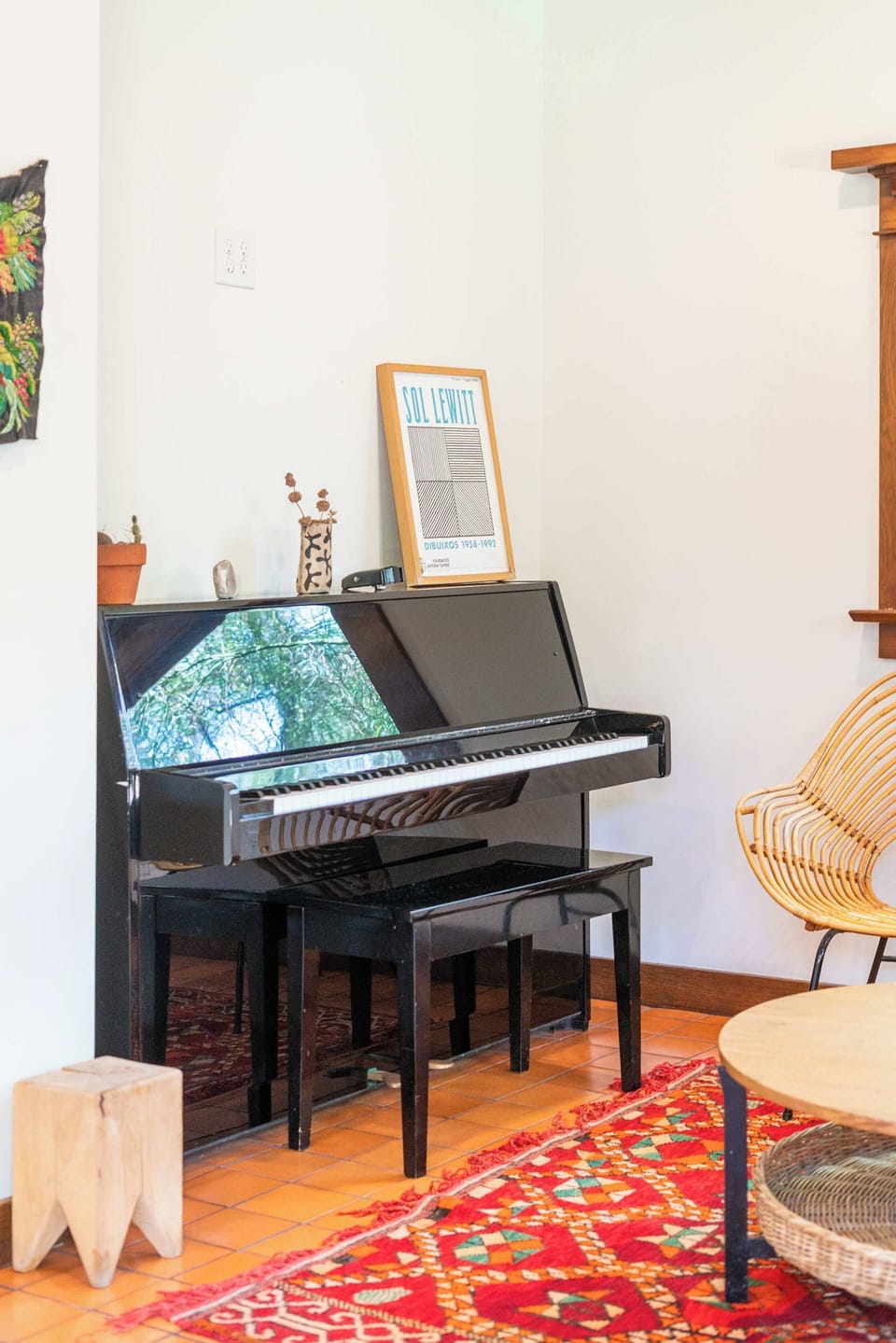 Library/Music Room — Close-Up of Black Upright Piano with Sol LeWitt Art Exhibition Print, Ceramic Vase, Terracotta Pots & Rattan Bucket Chair