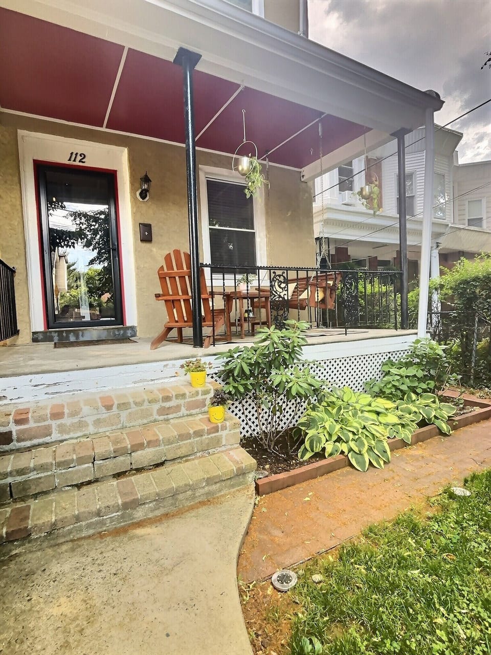 Front porch with swing and adirondack chair. 