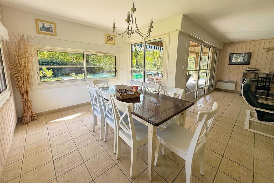 The dining table seats the whole group, with garden and pool views — breakfast delivery arrives here each morning.