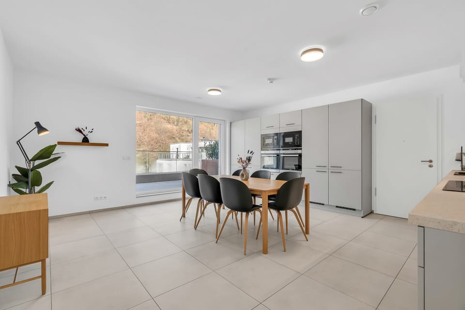 Bright living and dining space with modern furnishings, large windows, and a functional layout for short or extended stays